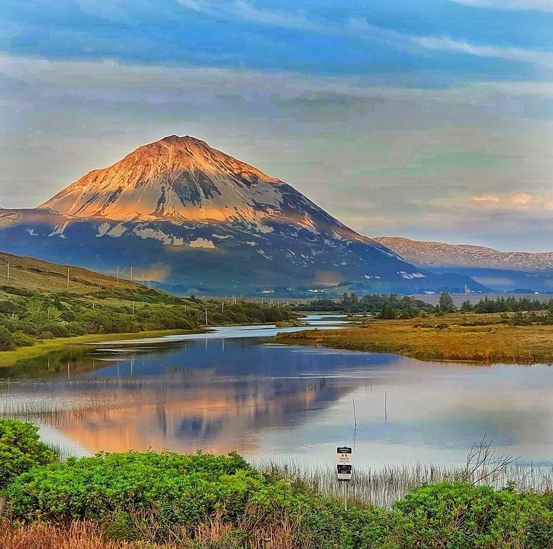 A mountain with a lake in the foreground and a clear sky.