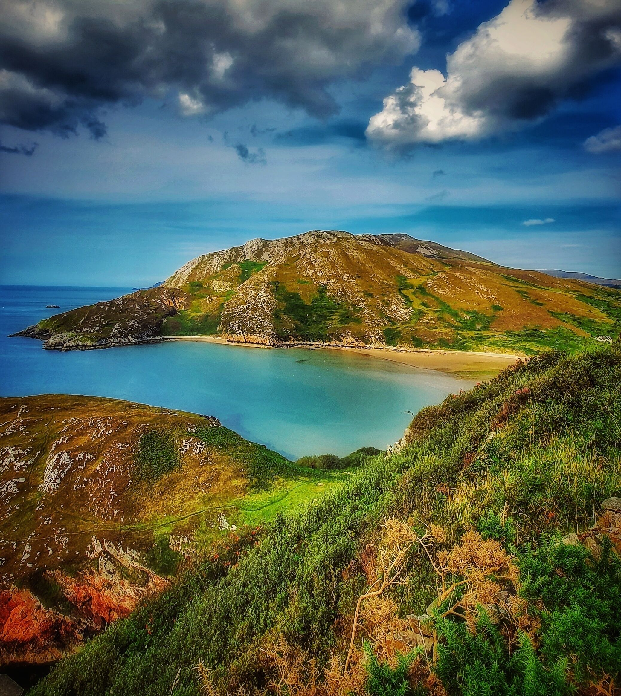 Un paysage côtier avec une montagne, une baie et un ciel dégagé.