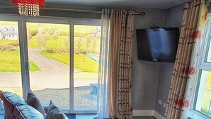 Ein modernes Wohnzimmer mit einem roten Ledersofa, einem roten Teppich und einem großen Fenster mit Vorhängen.
