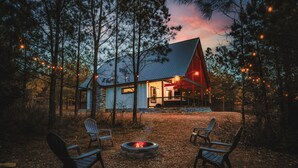A cabin with a fire pit and chairs in a forest setting. - Romantic Couples Cabin minutes from Casino Excitement & Lakeside Serenity (Broken Bow)