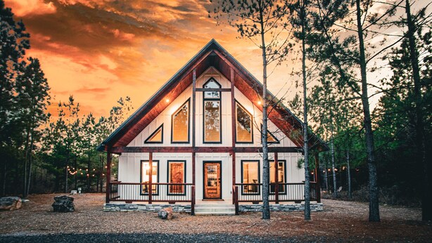 A two-story cabin with a steep gable roof, large windows, and a front porch. - Romantic Couples Cabin minutes from Casino Excitement & Lakeside Serenity (Broken Bow)