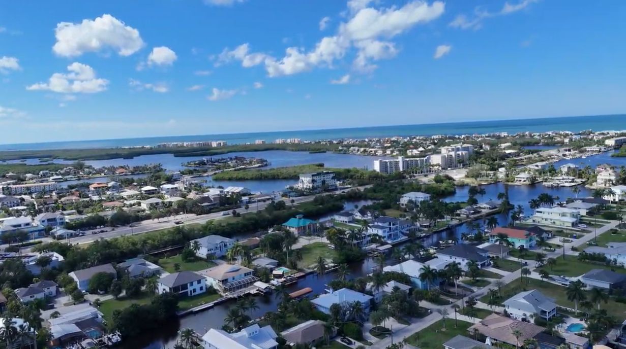 Une zone résidentielle côtière avec des maisons, un port de plaisance et un ciel bleu dégagé.
