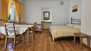 A room with a wooden floor, a bed, a table, and chairs. - La Pergola - Yellow - Studio Apartment (Rovinj)