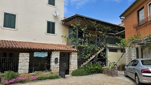 A courtyard with a stone building, a car, and a staircase leading to a balcony. - La Pergola - Yellow - Studio Apartment (Rovinj)