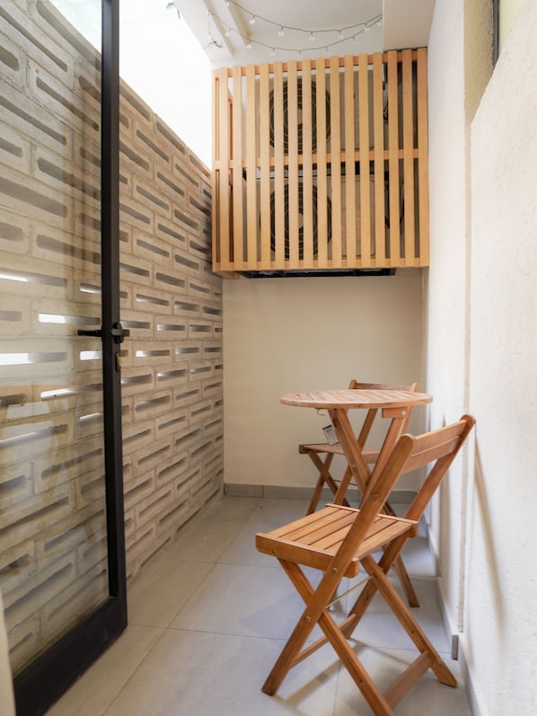 A narrow room with a brick-patterned wall, a wooden partition, and a small table with two chairs.