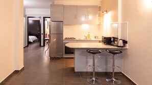 A modern kitchen with a refrigerator, stove, and bar stools.