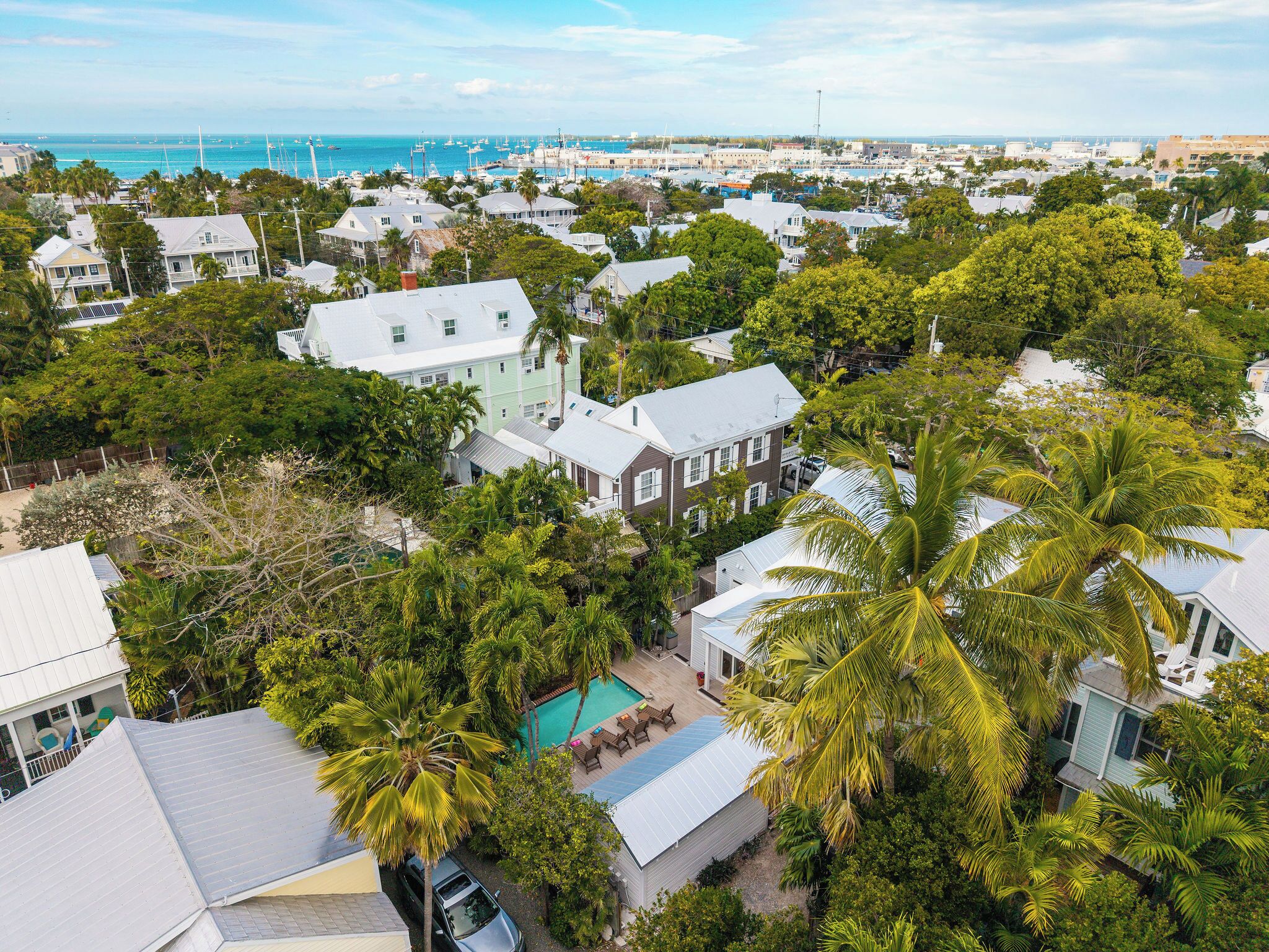 Un quartier résidentiel en bord de mer, avec des maisons, une piscine et, au loin, un port de plaisance.