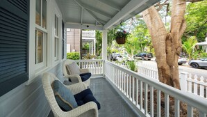 A porch with wicker chairs and a hanging planter.