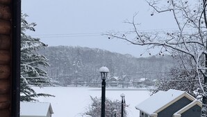 Schneebedeckte Landschaft mit einem Holzbauten, einer Straßenlaterne und Häusern im Hintergrund.