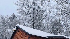 Eine Holzhütte mit schneebedecktem Dach, umgeben von Bäumen.