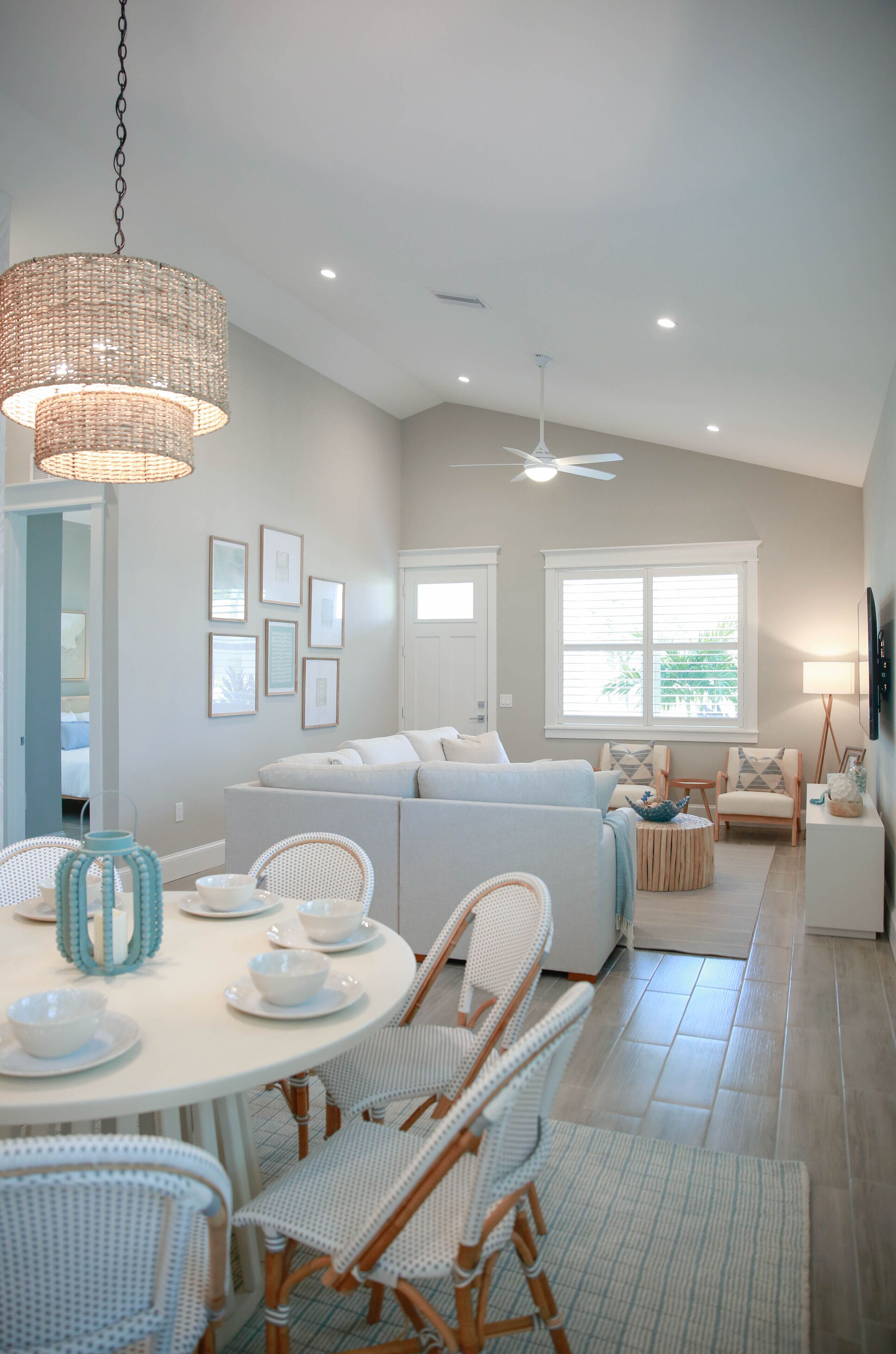 A modern living room with a white sofa, a dining table with chairs, and a ceiling fan.
