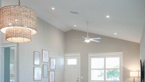 Un salon moderne avec un canapé blanc, une table à manger avec des chaises et un ventilateur de plafond.
