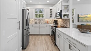 A modern kitchen with white cabinetry, a built-in oven, and a large island with a bowl.