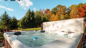 Ein Whirlpool in einer Außenanlage mit einer Holzterrasse und einer Rasenfläche.