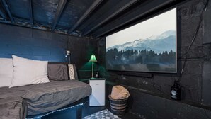 Ein gemütliches Schlafzimmer mit Bett, Lampe, Heizung, Fenster mit Bergblick und an der Wand montiertem Fernseher.