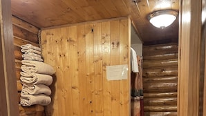 Un bagno in una cabina di legno, con il water, un porta asciugamani e una tenda da doccia.