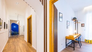 Un pasillo con suelo de madera, una pared azul decorativa y una puerta de madera.