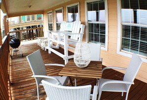 A wooden deck with white wicker furniture, including chairs and a table, and a grill. - Unwind by the Gulf at This Cozy Dune‑Front Cottage...Book Now! (Matagorda)