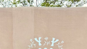 Una pared con un arco decorativo que da acceso a un santuario con una estatua.