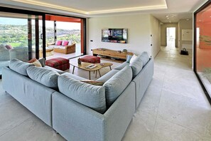 Ein modernes Wohnzimmer mit einem großen grauen Ecksofa, einem Couchtisch und einem flachbildfernseher, der an der Wand montiert ist.
