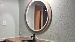 A bathroom with a vintage-style vanity, a round mirror, and patterned floor tiles. - Sunsets in Brookston (Brookston)