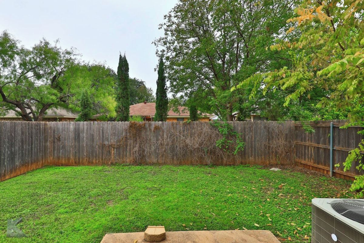 Ein Garten mit Holzzaun, Rasen und Baum.