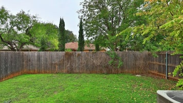 Ein Garten mit Holzzaun, Rasen und Baum.