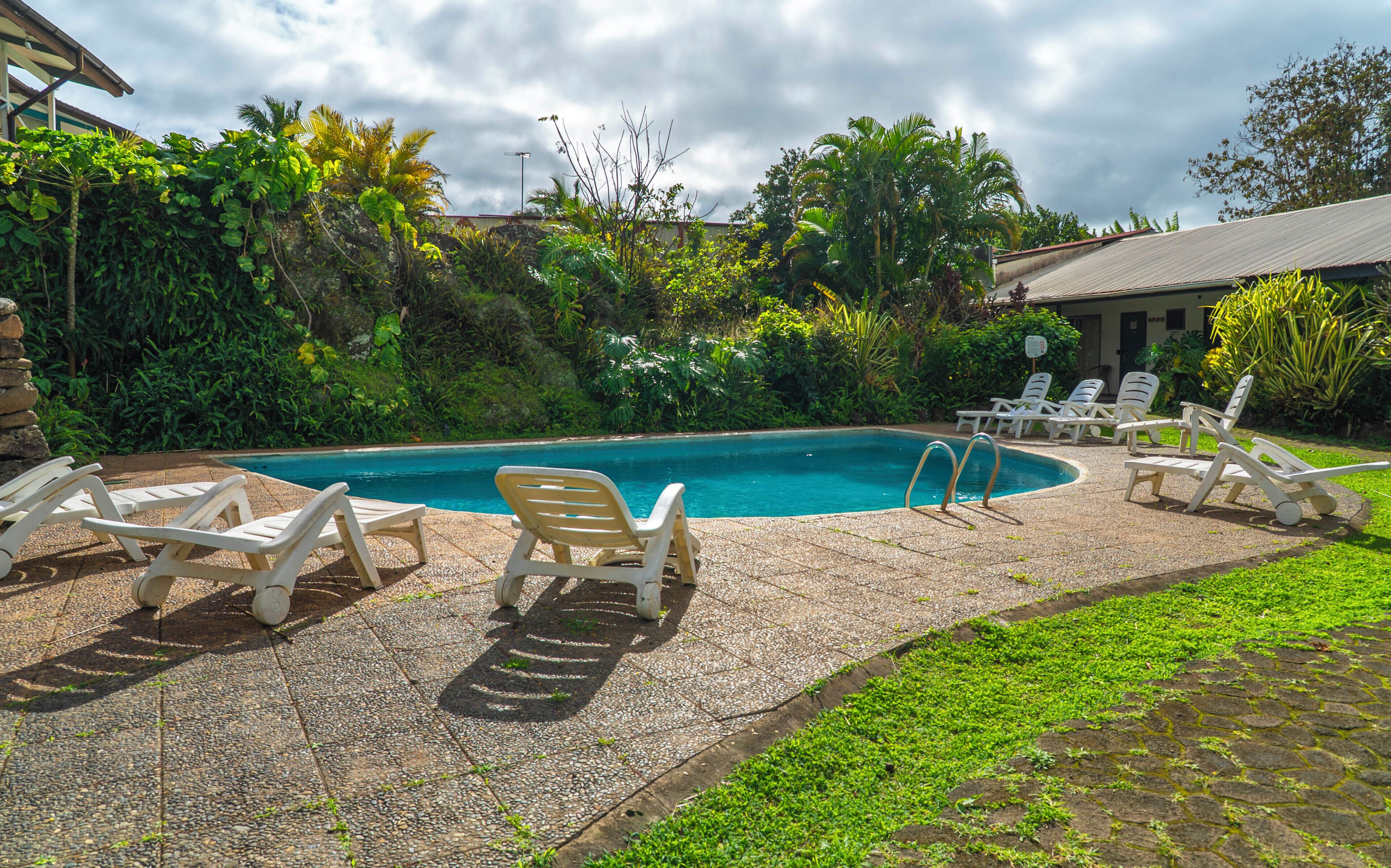 A swimming pool with lounge chairs and a stone patio.