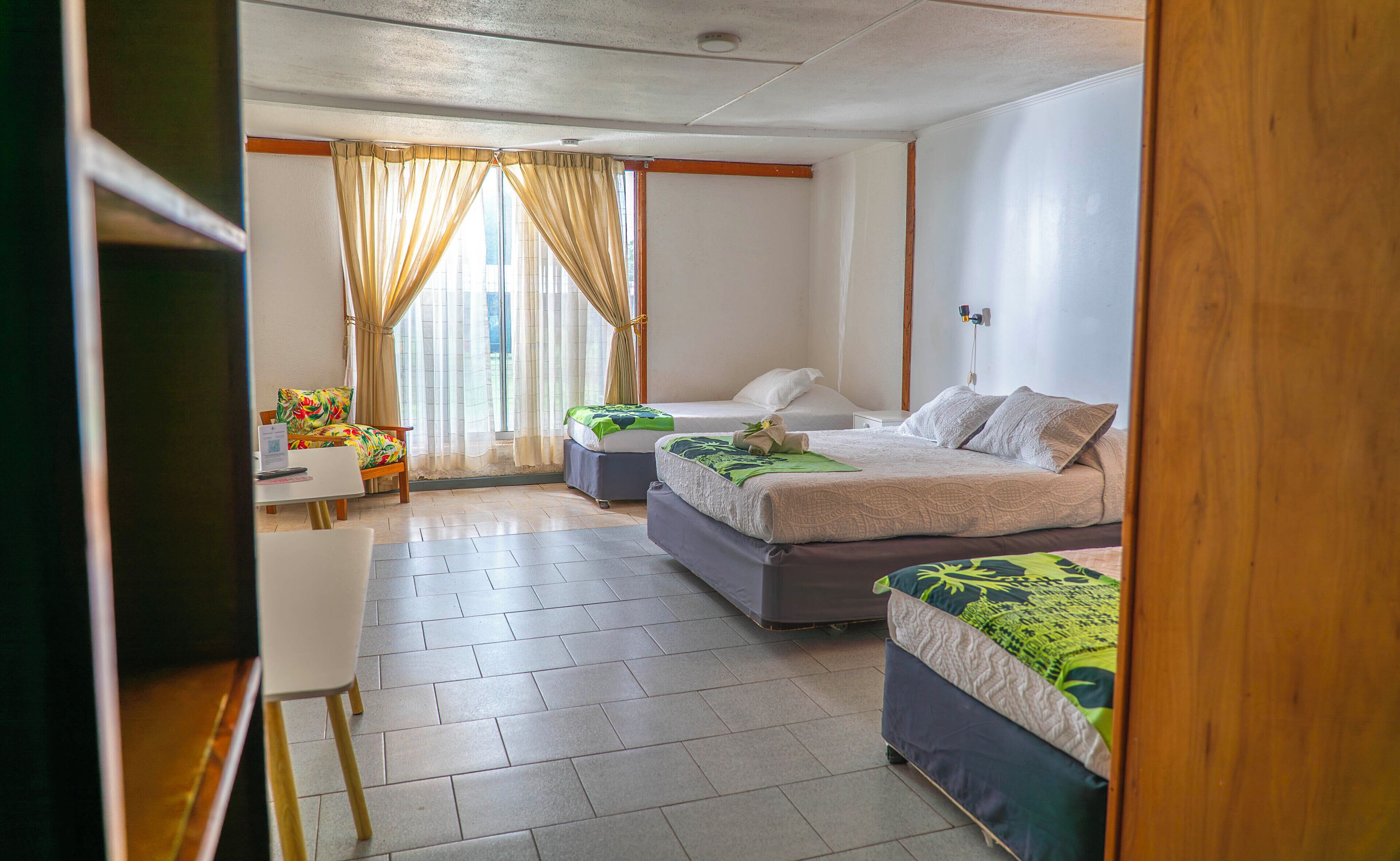 Habitación de hotel con dos camas, un escritorio y una silla.