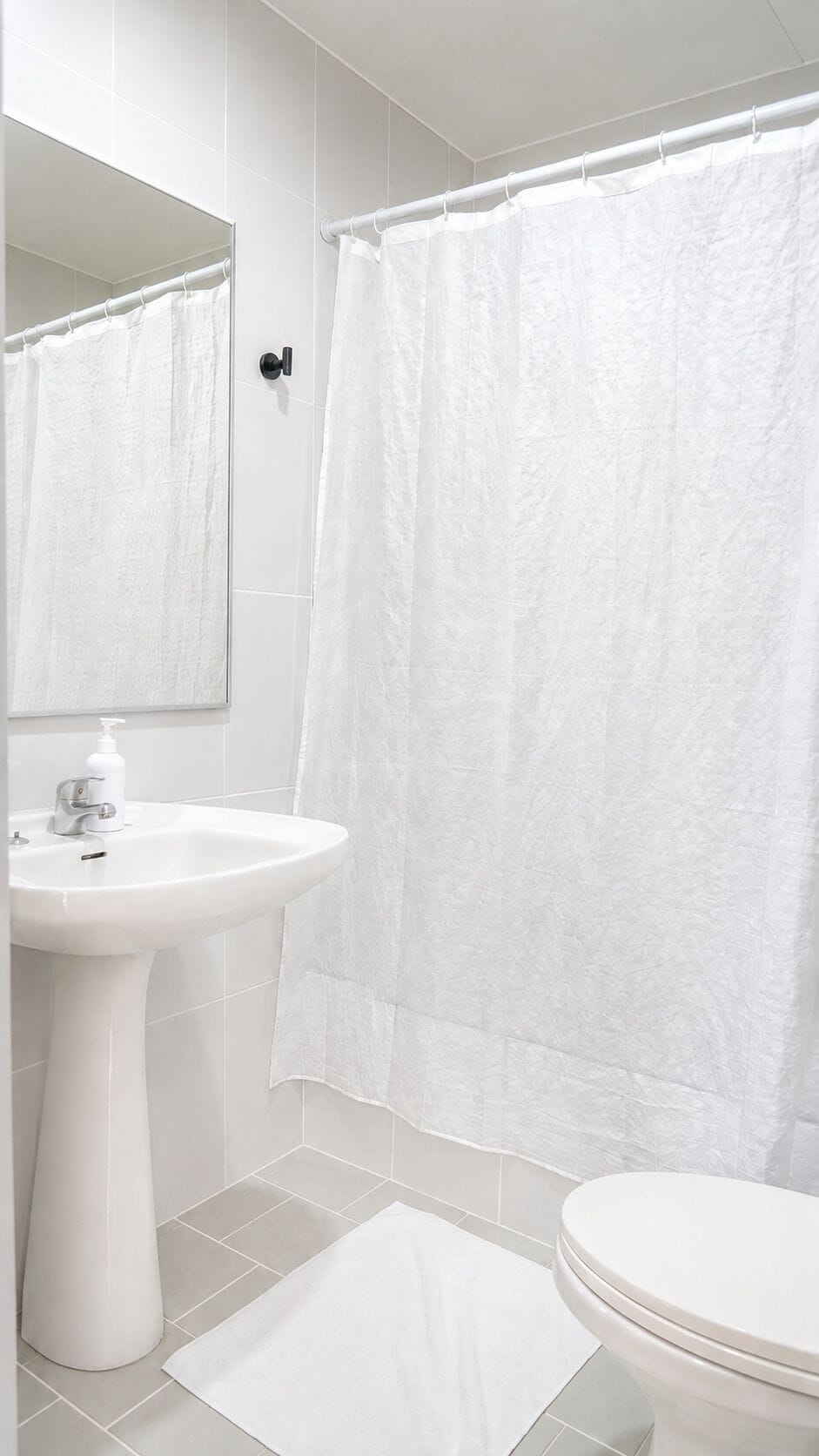 Un baño con lavamanos blanco, inodoro y cortina de ducha.
