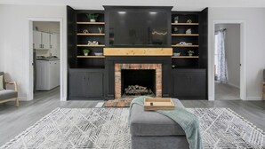 Een moderne woonkamer met een open haard, een ingebouwde entertainmentkast en een gezellige zithoek.