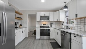 Een moderne keuken met witte kasten, roestvrijstalen apparatuur en een granieten aanrecht.