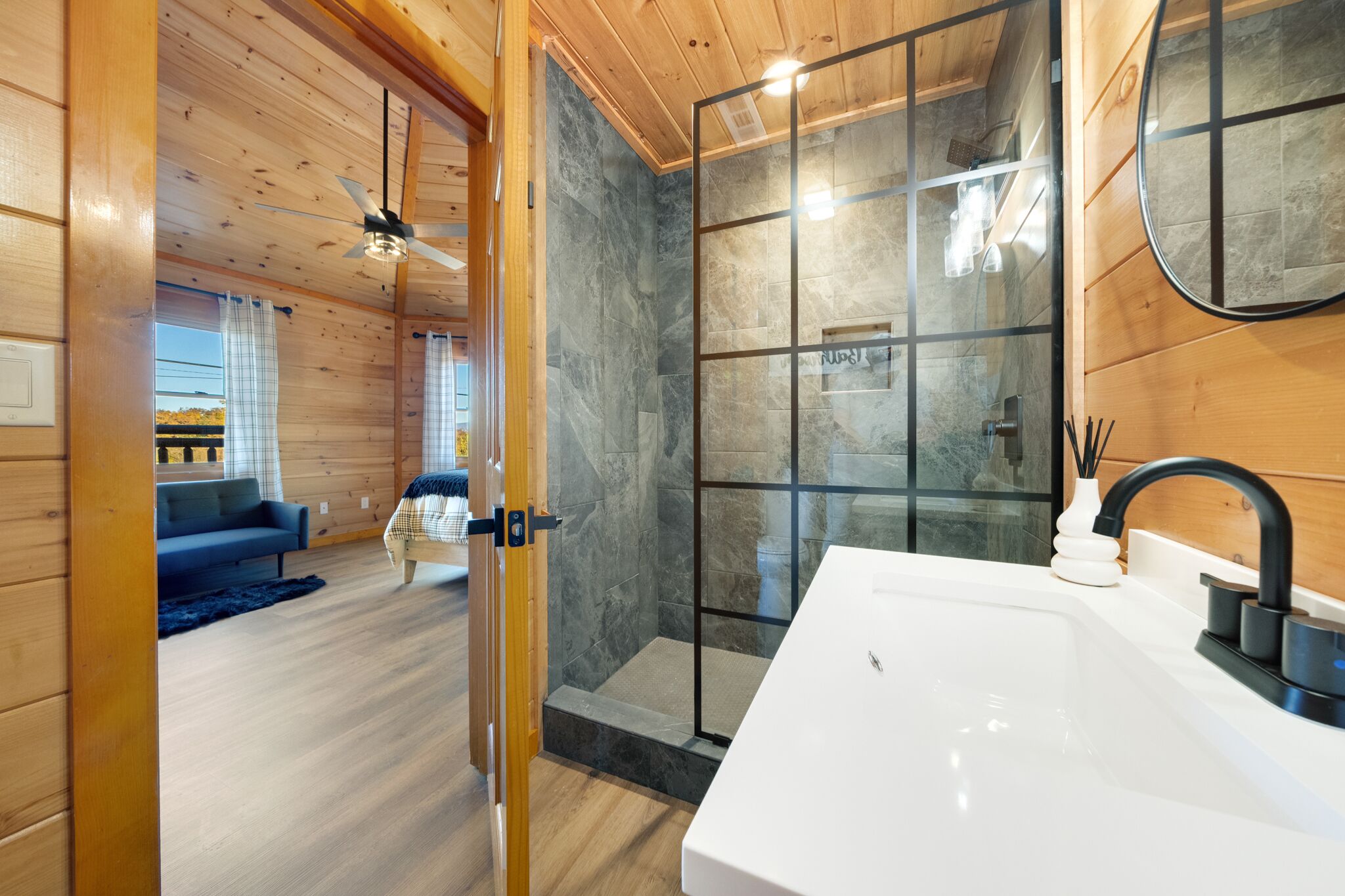 A modern bathroom with a large sink, a glass shower enclosure, and wooden walls.