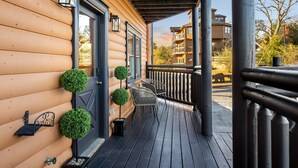 A wooden cabin with a porch, two potted plants, and a metal bench. - Indoor Pool Cabin w/ Theater - Near Douglas Lake (Sevierville)