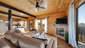 A modern log cabin interior with a living room, kitchen, and fireplace. - Indoor Pool Cabin w/ Theater - Near Douglas Lake (Sevierville)
