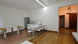 Eine moderne Küche mit weißen Schränken, einem Kühlschrank und einem Essbereich mit weißen Stühlen und einem Holztisch.