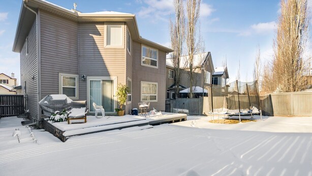 A two-story house with a covered patio, a trampoline, and a snow-covered yard. - Cozy 2-Bedroom Basement Suite Retreat Calgary (Calgary)