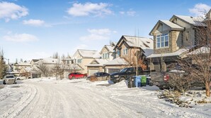 A residential street with houses, parked cars, and a snow-covered road. - Cozy 2-Bedroom Basement Suite Retreat Calgary (Calgary)