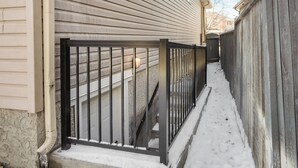 A snow-covered pathway leading to a house with a metal fence and a visible door. - Cozy 2-Bedroom Basement Suite Retreat Calgary (Calgary)