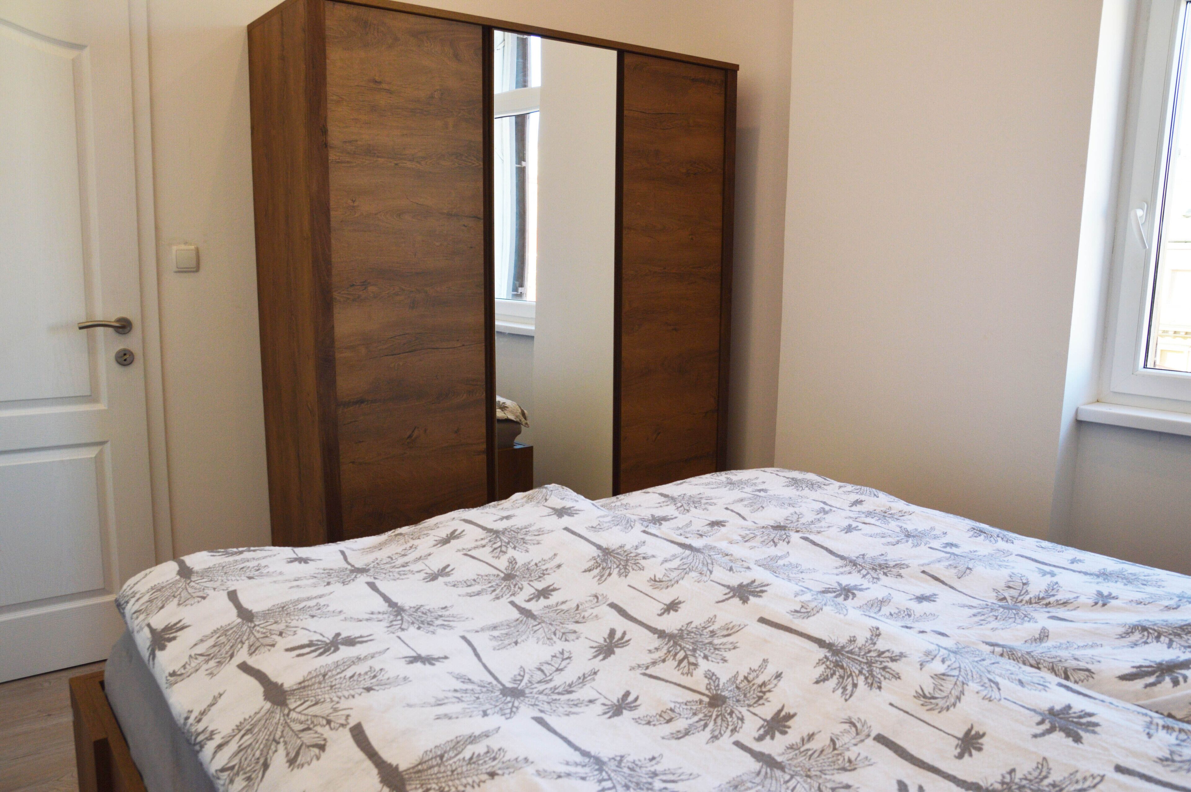 A bedroom with a bed, a wardrobe, and a window.