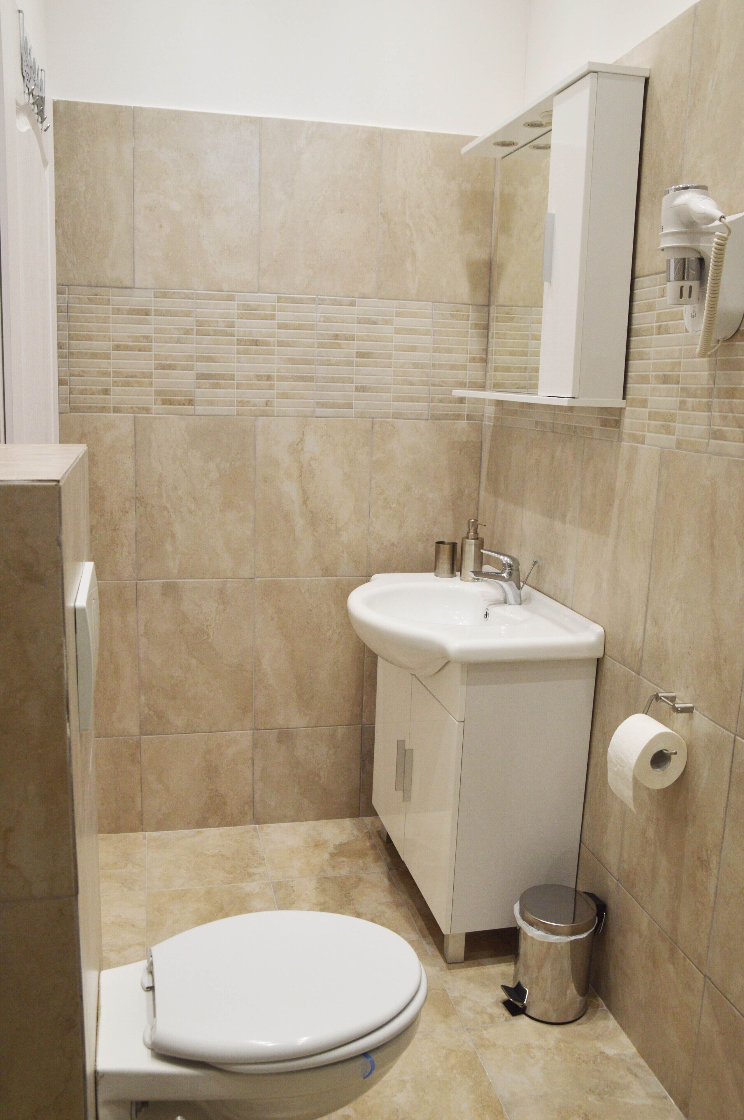 Une petite salle de bain avec des toilettes, un lavabo et un miroir au-dessus du lavabo.