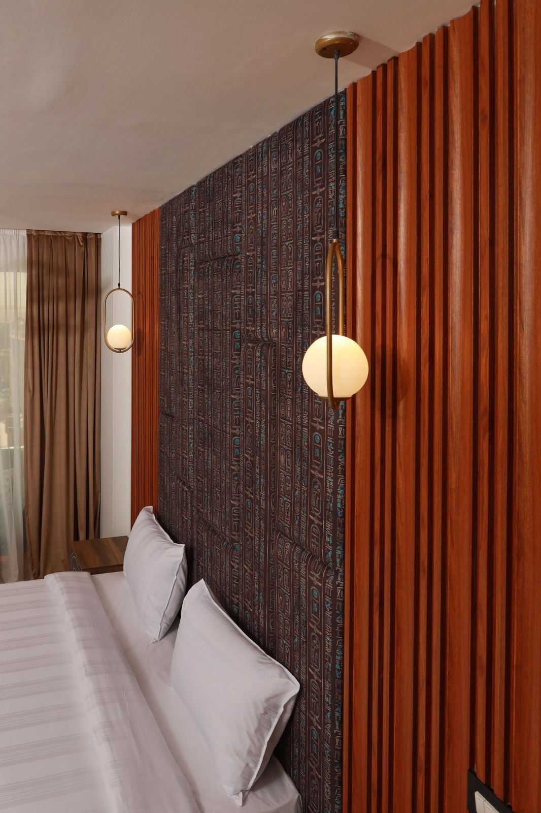 A hotel room with a bed, two wall-mounted lamps, and a patterned wall.