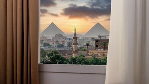 Une vue sur les pyramides au coucher du soleil, prise depuis une fenêtre avec des rideaux.