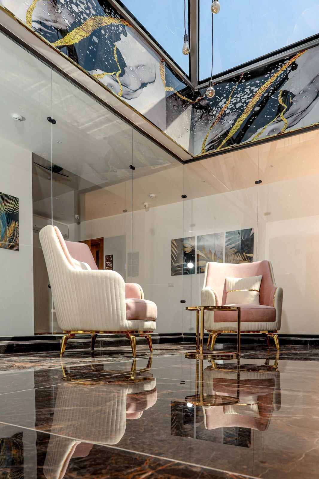 Una habitación amplia con dos sillones cómodos, techo de cristal y suelo de mármol.
