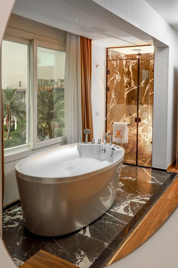 A modern bathroom with a freestanding bathtub, a glass shower enclosure, and a view of palm trees outside. - Guest House Paradise Top Roof Pyramids View (Giza)