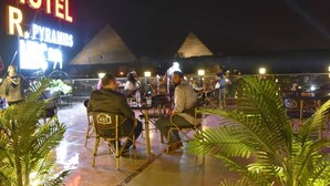 Un hôtel appelé « HOTEL R. PYRAMIDES », doté d’une terrasse et offrant une vue sur les pyramides en arrière-plan.