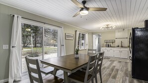 Une cuisine équipée d’une table à manger, de chaises, d’un ventilateur de plafond et d’un réfrigérateur.