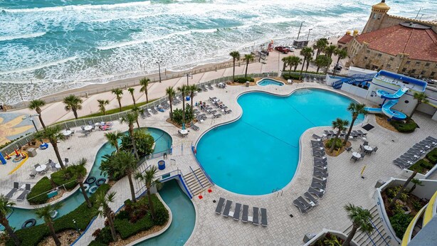 A resort with a large pool, beach access, and a water slide.