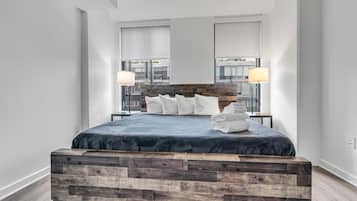 A modern bedroom with a wooden headboard, a large bed with white pillows, and two bedside lamps.