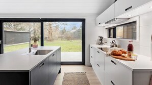 A modern kitchen with a large island, a sliding glass door to the backyard, and a built-in oven. - Awesome home in Stege with kitchen (Stege)